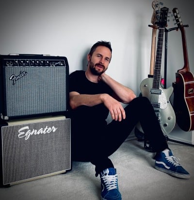 Erik sitting with guitar amps